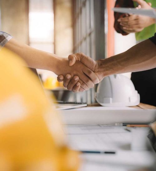 Construction workers, architects and engineers shake hands while working for teamwork and cooperation after completing an agreement in an office facility, successful cooperation concept.